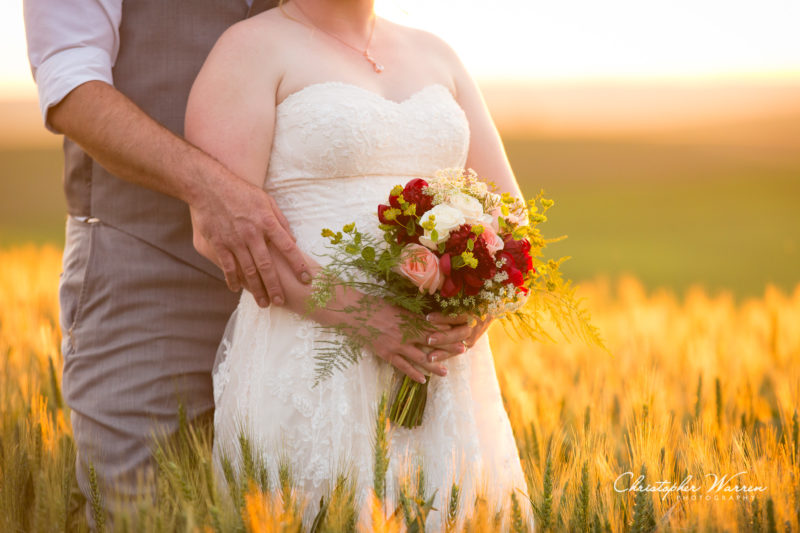 groom and bride holding bouquet at sunset